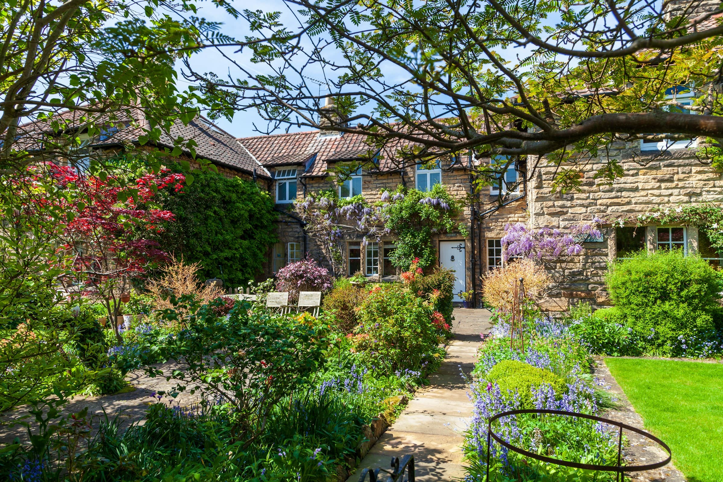 A traditional English stone cottage with a garden in front