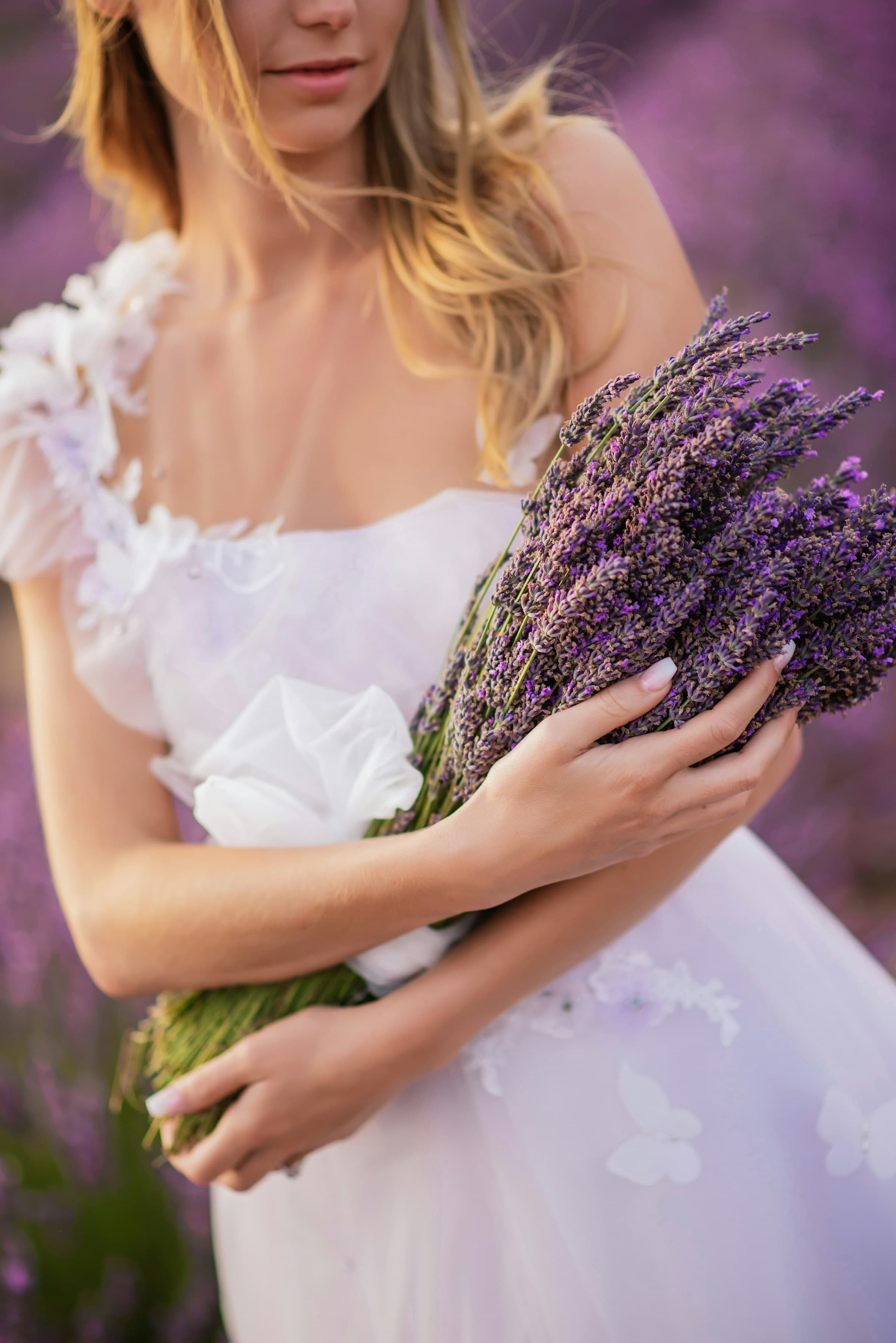 A bride holding a bouquet of lavender, cottage roses, and herbs