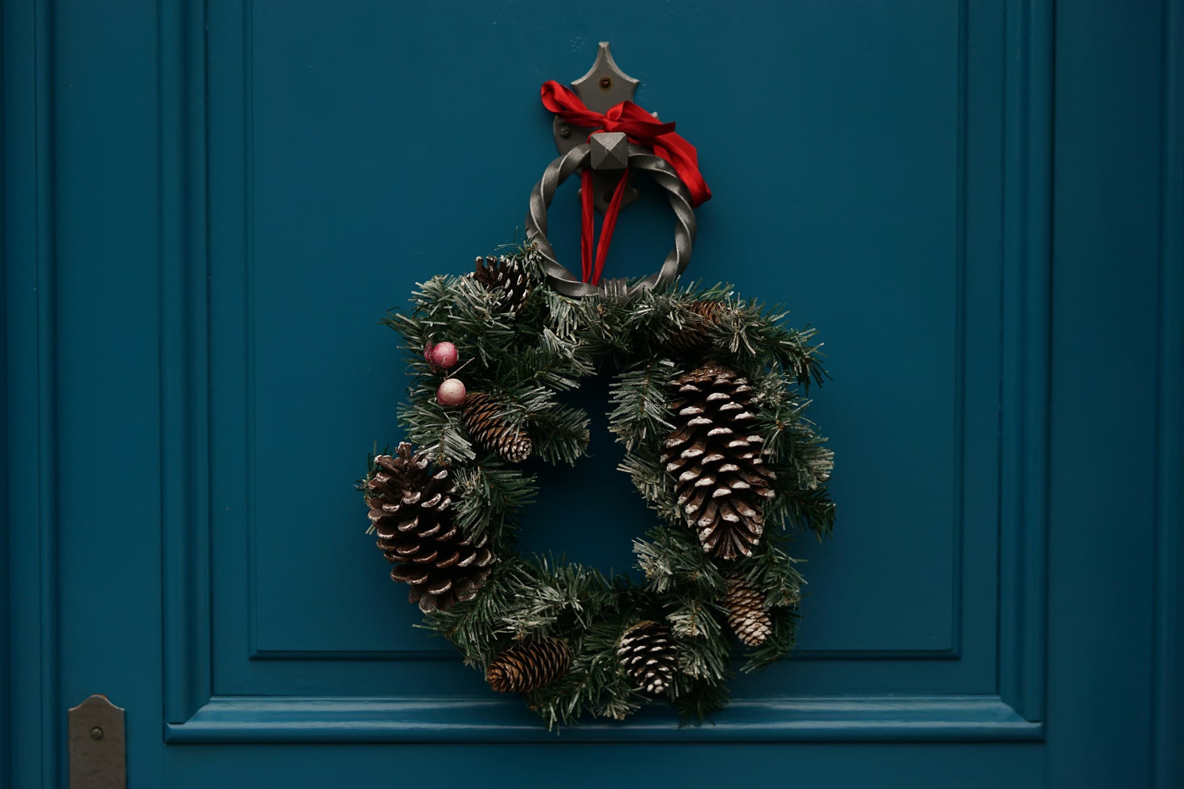 A green and brown seasonal foliage wreath hanging on a wooden door
