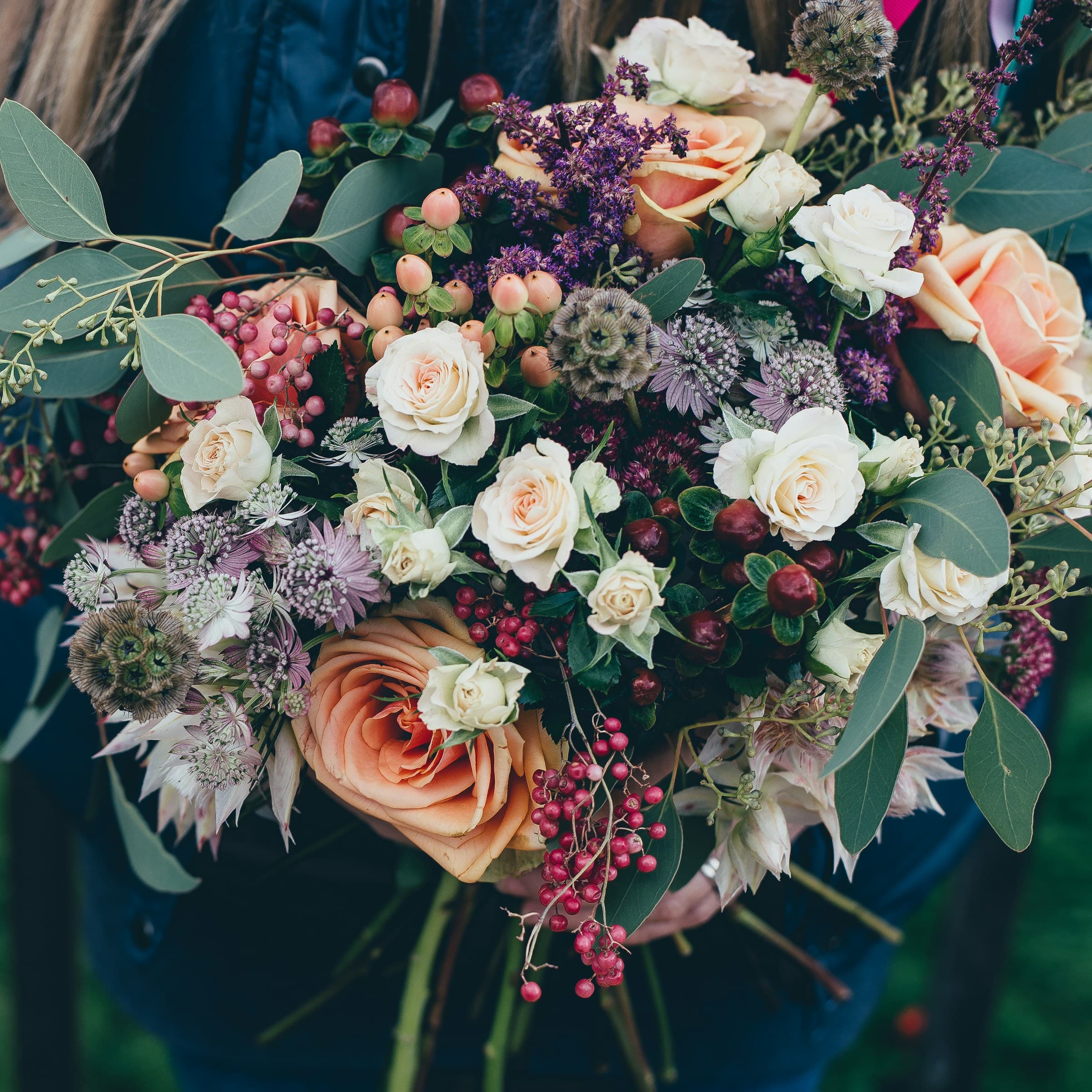 A loose hand-tied posy of cottage-garden roses in muted pinks and creams