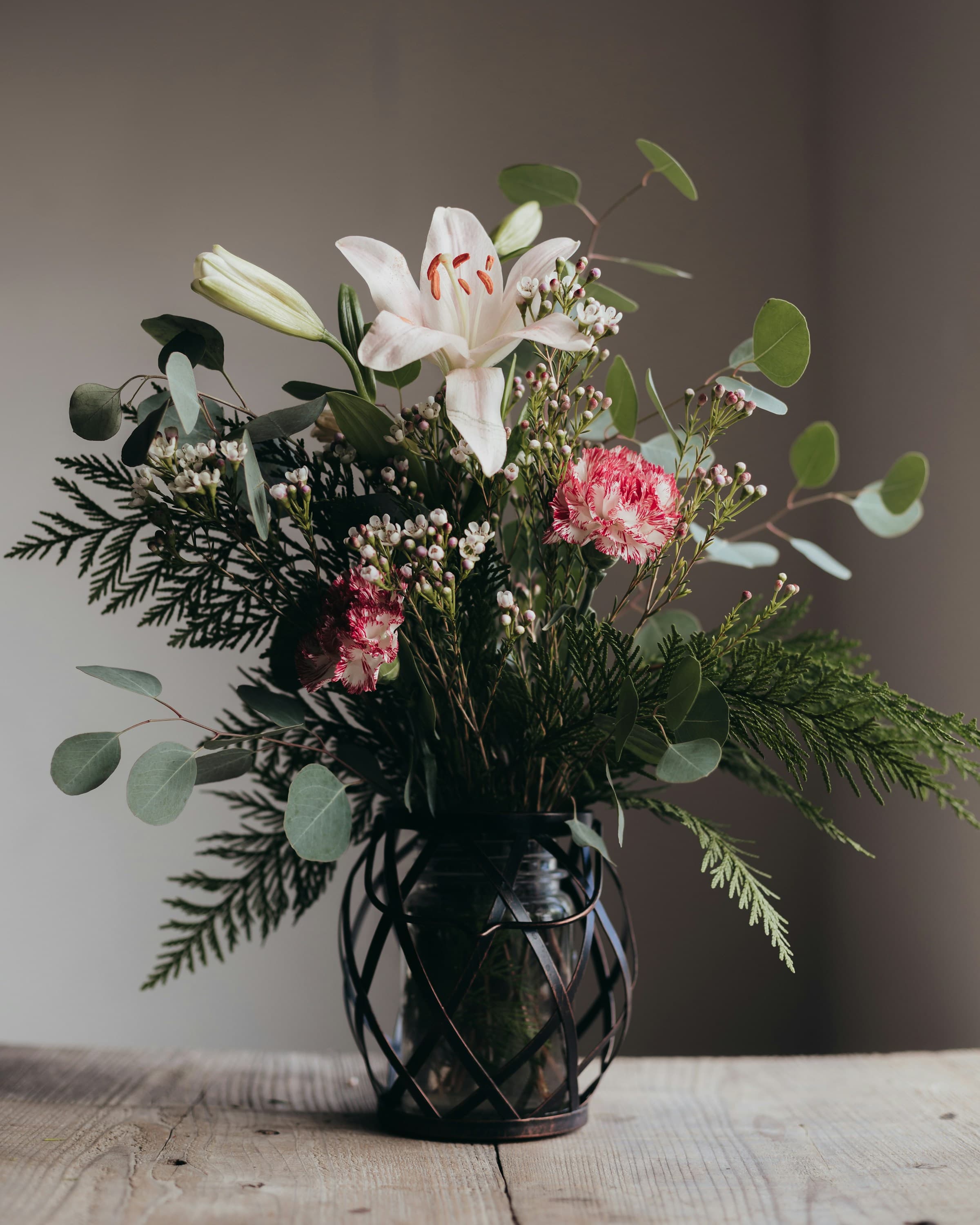 A vase of mixed seasonal flowers on a wooden tabletop